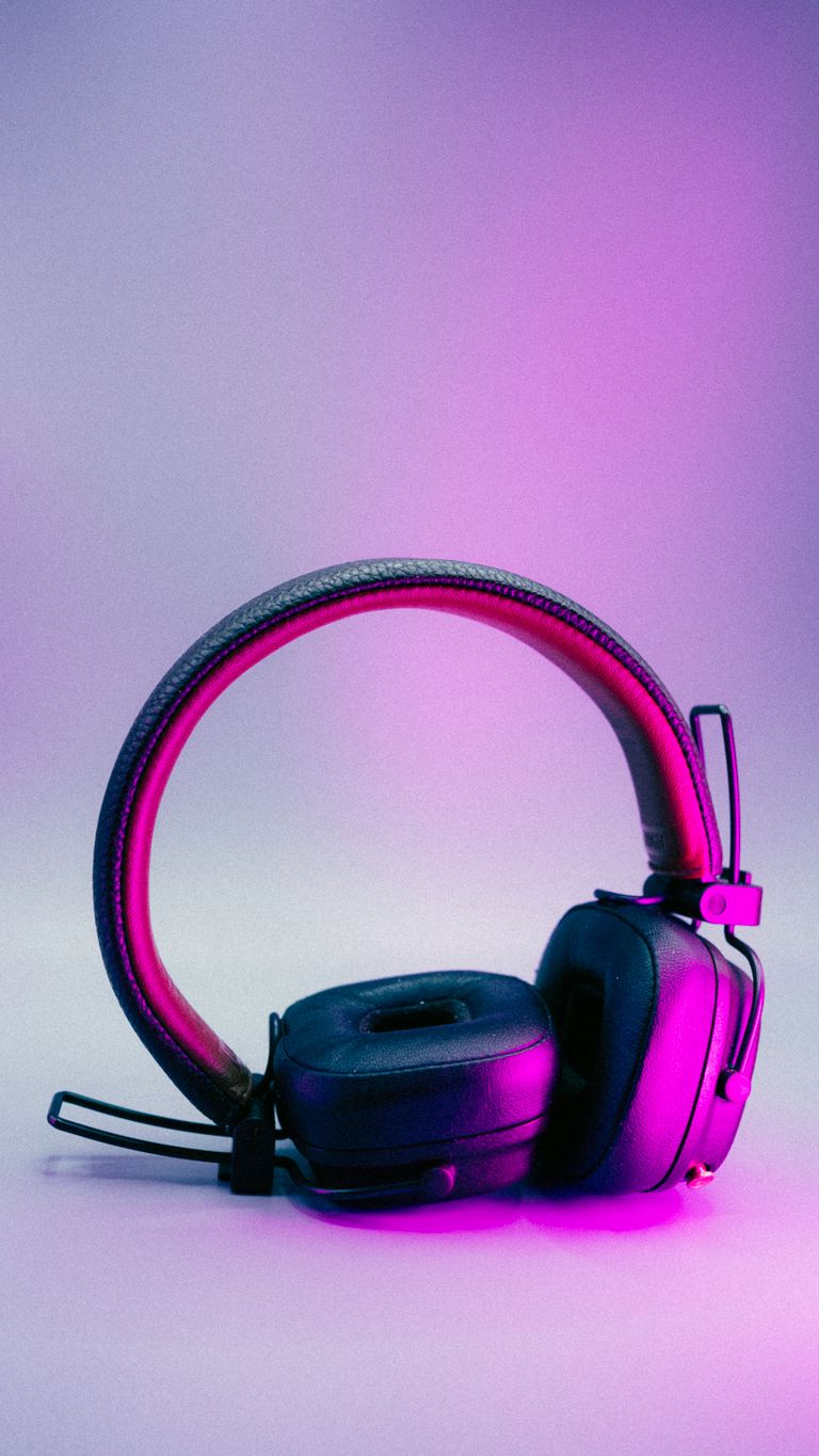 Close-up of stylish black headphones illuminated by vibrant purple light.